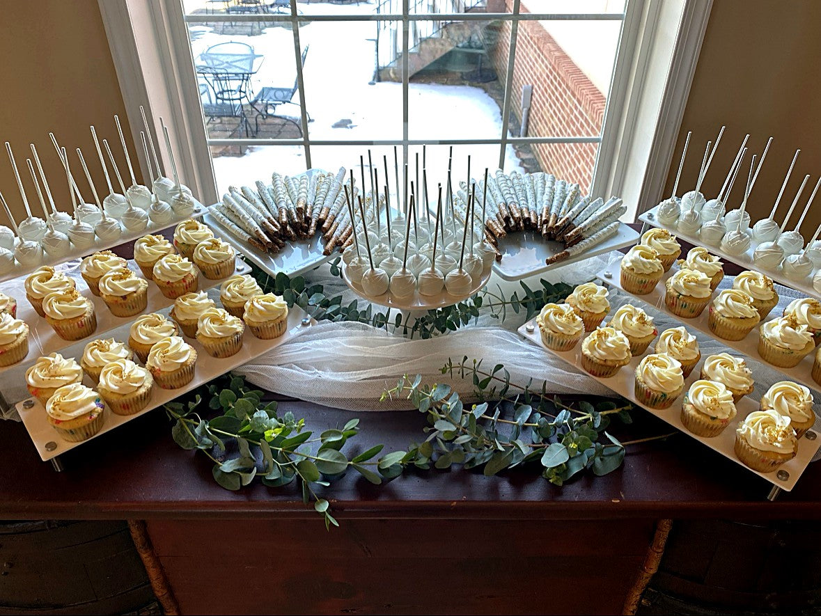 Dessert table by a window by LoveLe Sweets — white cupcakes, cake pops and dipped pretzel rods with eucalyptus